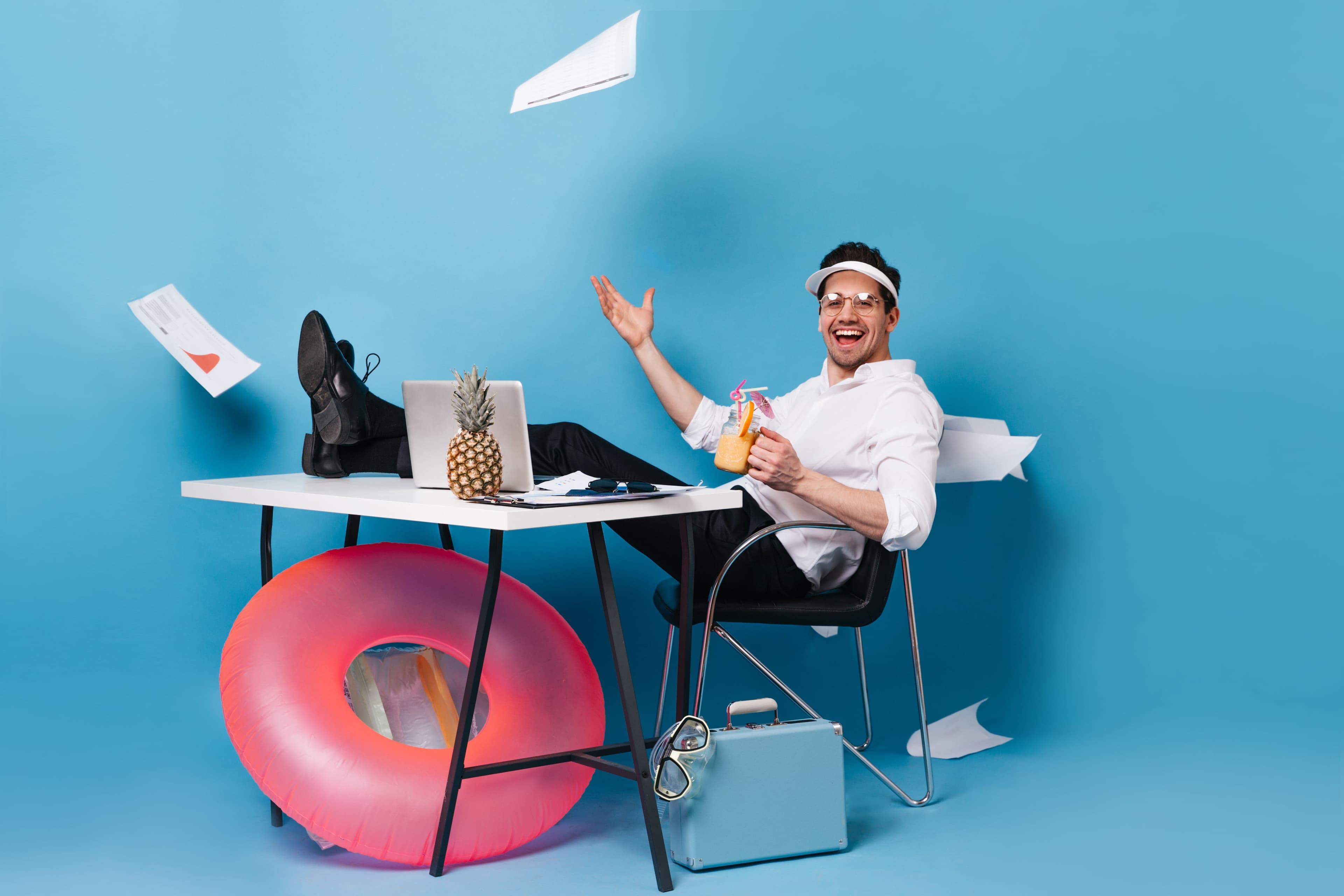 perky-businessman-suit-cap-scatters-graphics-enjoying-tasty-cocktail-sitting-table-with-laptop-rubber-ring-suitcase-blue-space.jpg